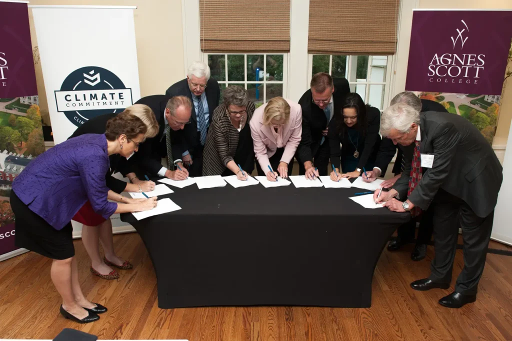 Group from Agnes Scott College signing papers around a shared table.